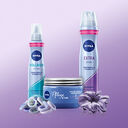 NIVEA Haarpflege mit Volumen- & Extra-Stark-Spray, Pflege-Creme, Haargummis & Scrunchie auf lila Hintergrund. - Link zur Markenseite/Haarstyling