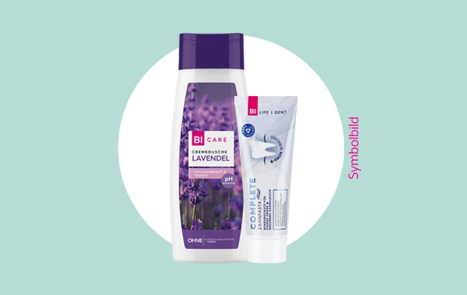 BI CARE Cremedusche Lavendel und BI LIFE DENT Complete Zahnpasta vor einem hellblauen Hintergrund als Symbolbild.