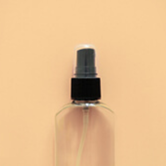 Eine Sprühflasche aus Glas auf orangenem Hintergrund.
