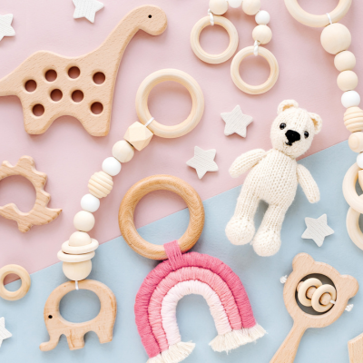 Holz-Babyspielzeug mit Dino, Beißringen, Plüschbär und Regenbogen auf rosa-blauem Hintergrund – nachhaltig & kindgerecht.
