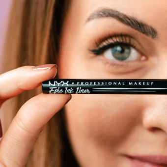 Nahaufnahme einer Frau, die einen Eyeliner vor dem Gesicht hält. Link zu den Neuheiten.