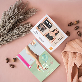 Flatlay mit Trockenblumen, Eicheln, Stoff und offenem Buch auf rosa Hintergrund