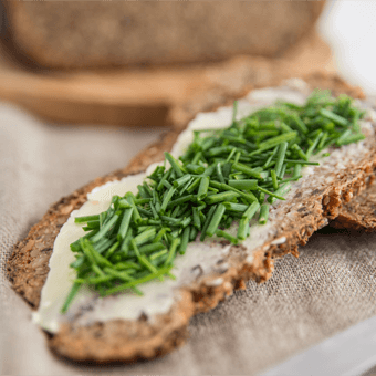 Ein Butterbrot mit Schnittlauch auf einem Holzbrett.