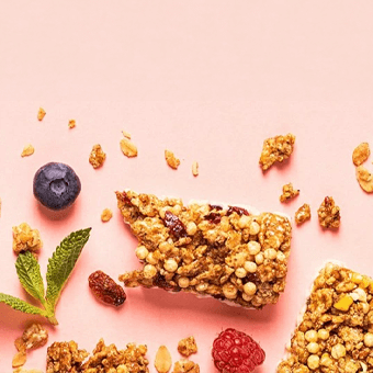 Granola-Riegel mit Haferflocken, Himbeeren, Blaubeeren und Minze auf rosa Hintergrund – gesunder Snack-Content.