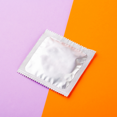 Silber Kondomverpackung auf lila/orangenem Hintergrund