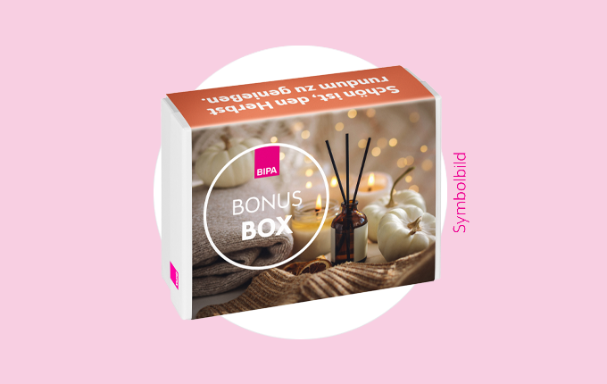 BIPA Bonus Box mit Duftkerzen, Diffuser & Kürbissen auf Strickdecke – herbstliche Wohlfühlprodukte entdecken.