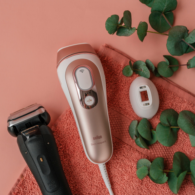 Braun Silk-expert Pro IPL, Rasierer auf rosa Handtuch mit Eukalyptusblättern arrangiert