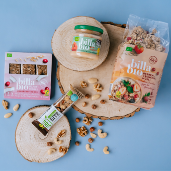 BILLA Bio Produkte – Granola, Nussriegel & Fruchtaufstrich auf Holz mit Nüssen, ideal für bewusste Ernährung.