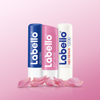 Labello Lippenpflege: Original, Soft Rosé & Med Repair vor rosa Hintergrund mit Rosenblättern. - Link zur Markenseite/Labello