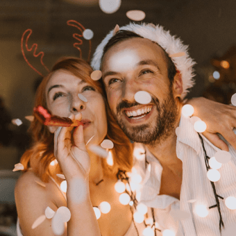 Zwei Personen in festlicher Kleidung vor Weihnachtslichtern, Gesichter unscharf – Feiertagsstimmung pur.