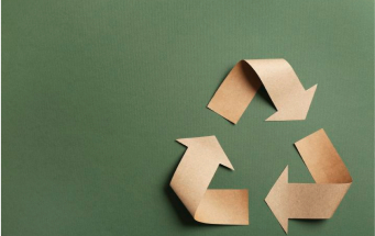 Recycling-Symbol aus braunem Papier auf grünem Hintergrund – Hinweis auf reduzierten Papierverbrauch bei BIPA