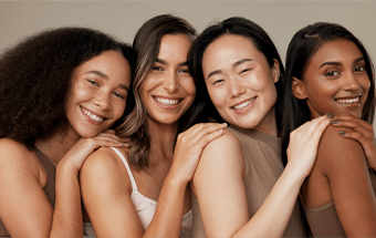 Vier Frauen mit verschiedenen Hauttönen stehen Schulter an Schulter – Farbtyp analysieren. Copyright: Getty Images. - Link zu Blogartikel Welcher Farbtyp bin ich