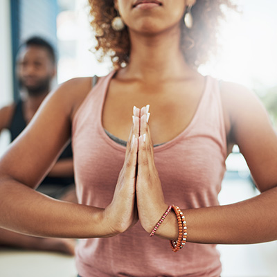 Frau in rosa Tanktop mit gefalteten Händen in Yoga-Pose,