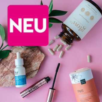 Vitamins, Serum, Mascara und PMS-Supplement auf rosa Hintergrund mit Blättern und Stein für Wellness. Linkt zu Neuheiten