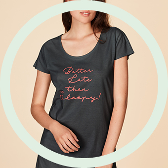 Eine Frau in einem grauen Nachthemd vor orangenem Hintergrund.