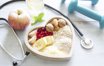 Herzförmiger Teller mit gesunden Lebensmitteln, Stethoskop und Hanteln – betriebliche Gesundheitsförderung