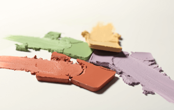 Bunte Colour Correction Farben auf weißem Hintergrund – Make-up Palette mit Grün, Gelb, Lila und Rot für Beauty-Looks. - Link zu Blogartikel Color correcting Make-Up