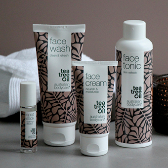 Gesichtspflegeprodukte mit Teebaumöl: Gesichtswasser, Gesichtscreme, Gesichtswaschgel und Serum vor Handtuch. - Link zu Markenseite/Gesicht