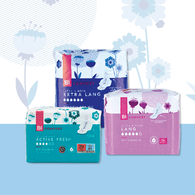 Damenbinden in drei Größen vor Blumenhintergrund – hygienischer, komfortabler Periodenschutz für jeden Bedarf.