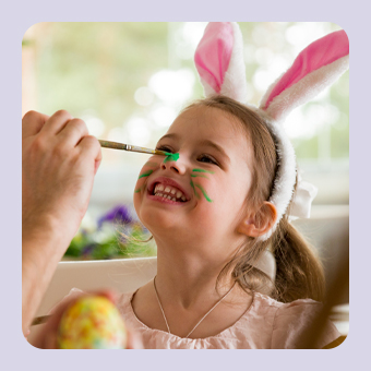Kind mit Hasenohren wird für Ostern geschminkt und hält ein bunt bemaltes Osterei in fröhlicher Frühlingsszene.