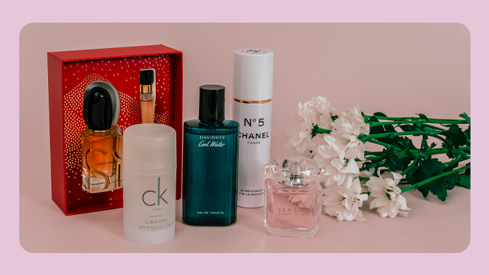 Verschiedene Parfums und Duftsets von Marken wie Chanel, Calvin Klein und Davidoff, dekorativ arrangiert neben Blumen.