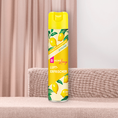 BI Home Living Lufterfrischer vor beigen Vorhängen und Sofa.