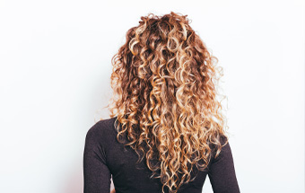 Lockiges langes Haar von hinten – Pflege‑Tipps für definierte Locken und gesundes Haar.