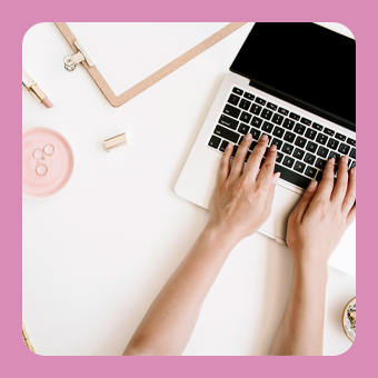 Hände tippen auf Laptop an hellem Schreibtisch mit Schreibunterlagen; moderner Workspace für digitales Arbeiten.