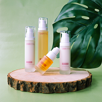 CBD Vital Naturkosmetik – vier Pflegeprodukte mit CBD auf Holzplatte vor grünem Hintergrund arrangiert.