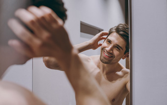 Person stylt kurze Haare vor dem Spiegel – Tipps für Männerfrisuren und modernes Hairstyling.