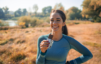 Person im Freien mit Proteinriegel – gesunde Fitness‑Snacks für aktive Outdoor‑Tage.