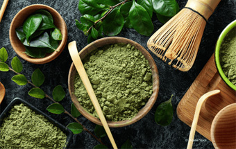 Matcha‑Pulver und Teezubehör auf dunkler Fläche – Zutaten für traditionellen Matcha‑Tee.