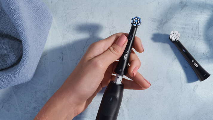 Schwarze elektrische Zahnbürste auf Marmor mit Eukalyptus & Handtuch – stilvolle & moderne Zahnpflege.