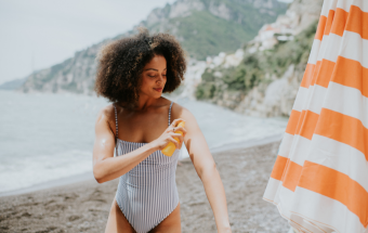 Frau trägt am Strand Sonnencreme auf. Copyright: Getty Images