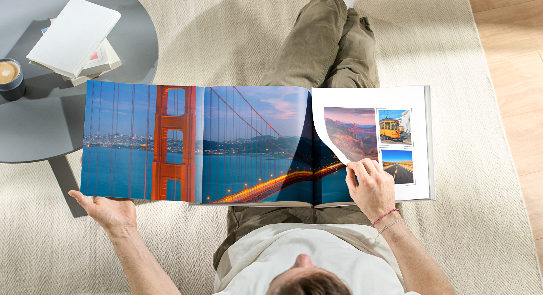 Eine Person öffnet eine CEWE FOTOBUCH mit der Panoramaseite mit Fotos aus San Francisco, gesehen von oben