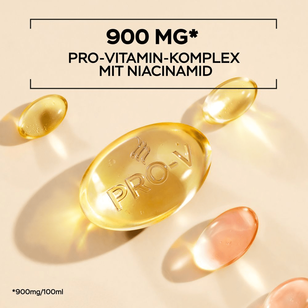 Mehrere goldene, transparente Kapseln, die an Vitamine erinnern, liegen auf einem beigefarbenen Untergrund. Eine der Kapseln ist größer und hat ein 'PRO-V' Logo eingeprägt. Darüber steht in schwarzer Schrift: 900 MG PRO-VITAMIN COMPLEX MIT AMINOSÄUREN.