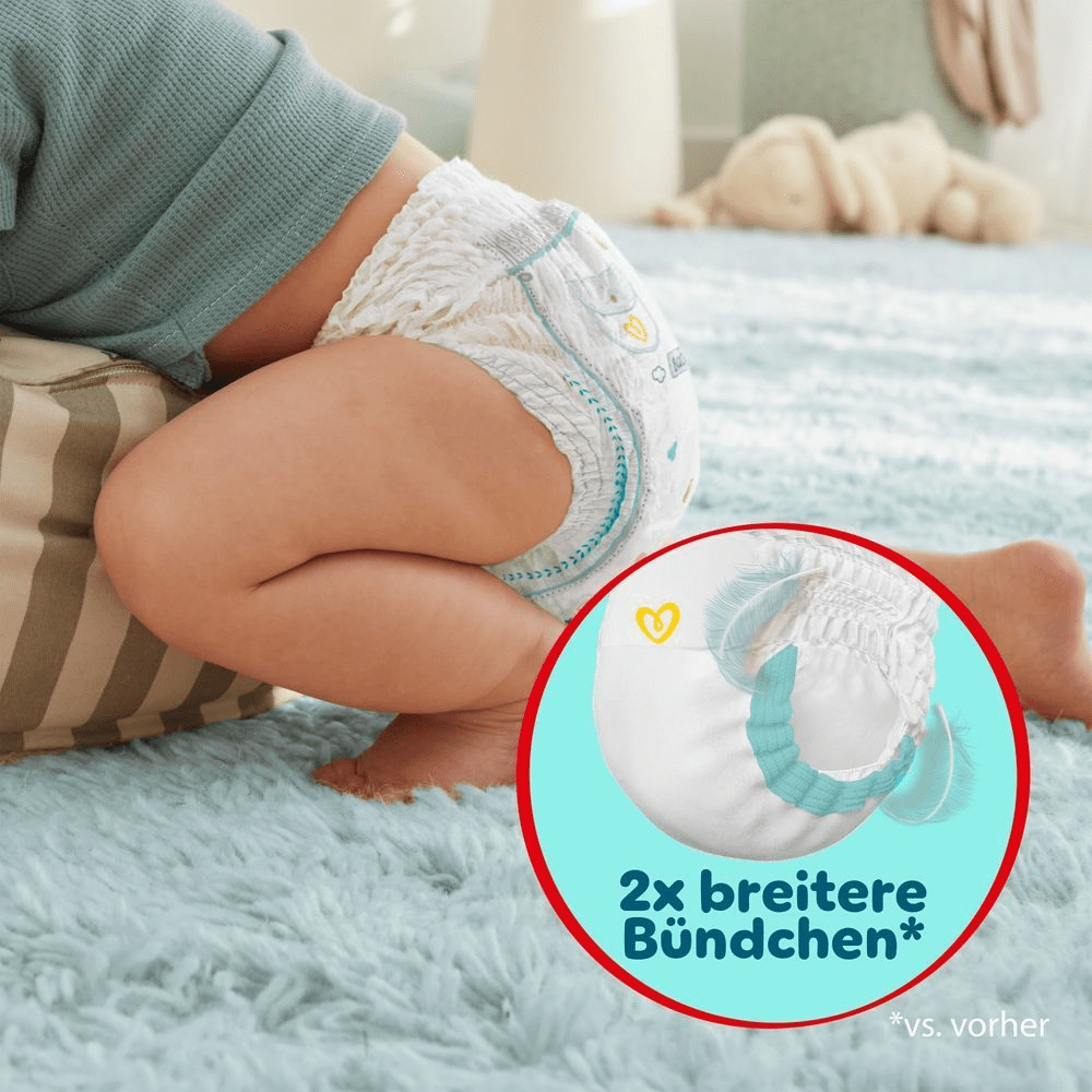 Nahaufnahme eines Babys, das Pampers Premium Protection Pants mit 2x breiteren Bündchen vs. vorher trägt, für eine sicherere Passform und ultra weiche Materialien. Das Baby krabbelt auf einem weichen Teppich.