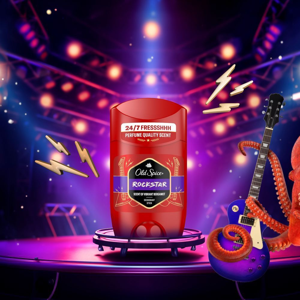 Old Spice Rockstar Deodorant-Stick auf einer Bühne mit Gitarre, die den Duft als rockigen, lebendigen Duft inszeniert. [ES] Old Spice Rockstar desodorante en barra, con fragancia vibrante de bergamota, evoca un ambiente de concierto de rock.;