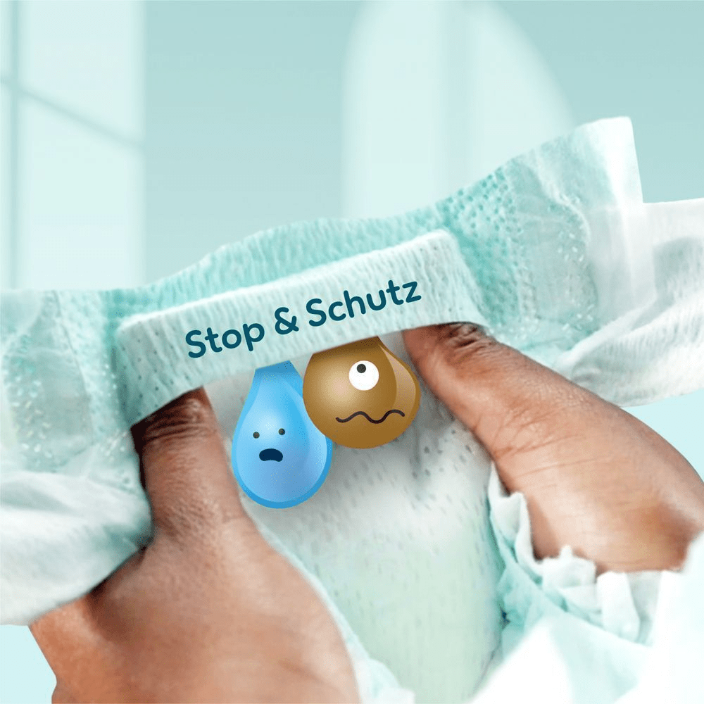 Eine Person hält eine Pampers Premium Protection Windeln in der Hand mit beiden Daumen in das Stop & Schutz Täschchen geschoben zur Verdeutlichung, wie die Windel Auslaufen am Rücken verhindert.