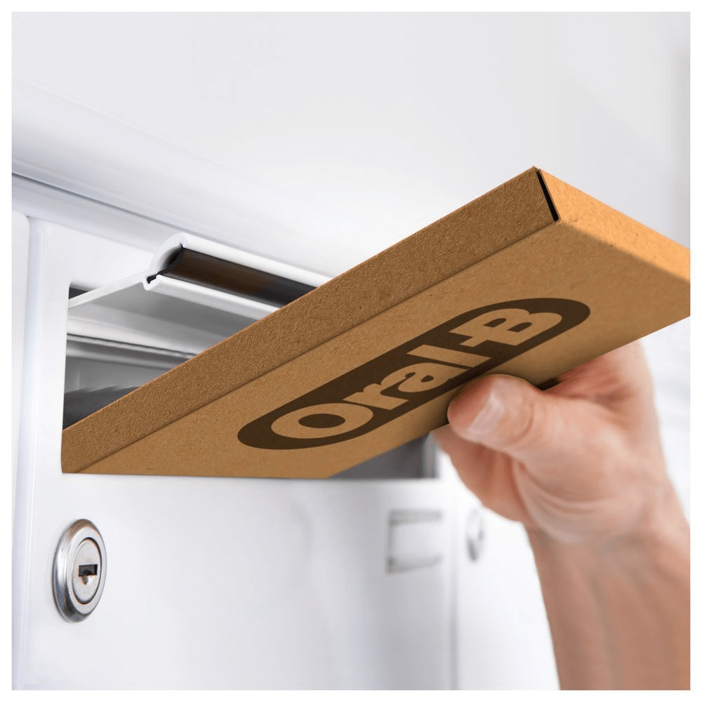Oral-B Produkt wird bequem per Post geliefert, direkt in den Briefkasten. [EN] Oral-B package being delivered directly to a customer’s mailbox, highlighting convenient home delivery. [IT] Consegna a domicilio di una confezione Oral-B, per una comoda igiene orale senza uscire di casa. [ES] Entrega a domicilio de un paquete de Oral-B directamente en el buzón del cliente.
